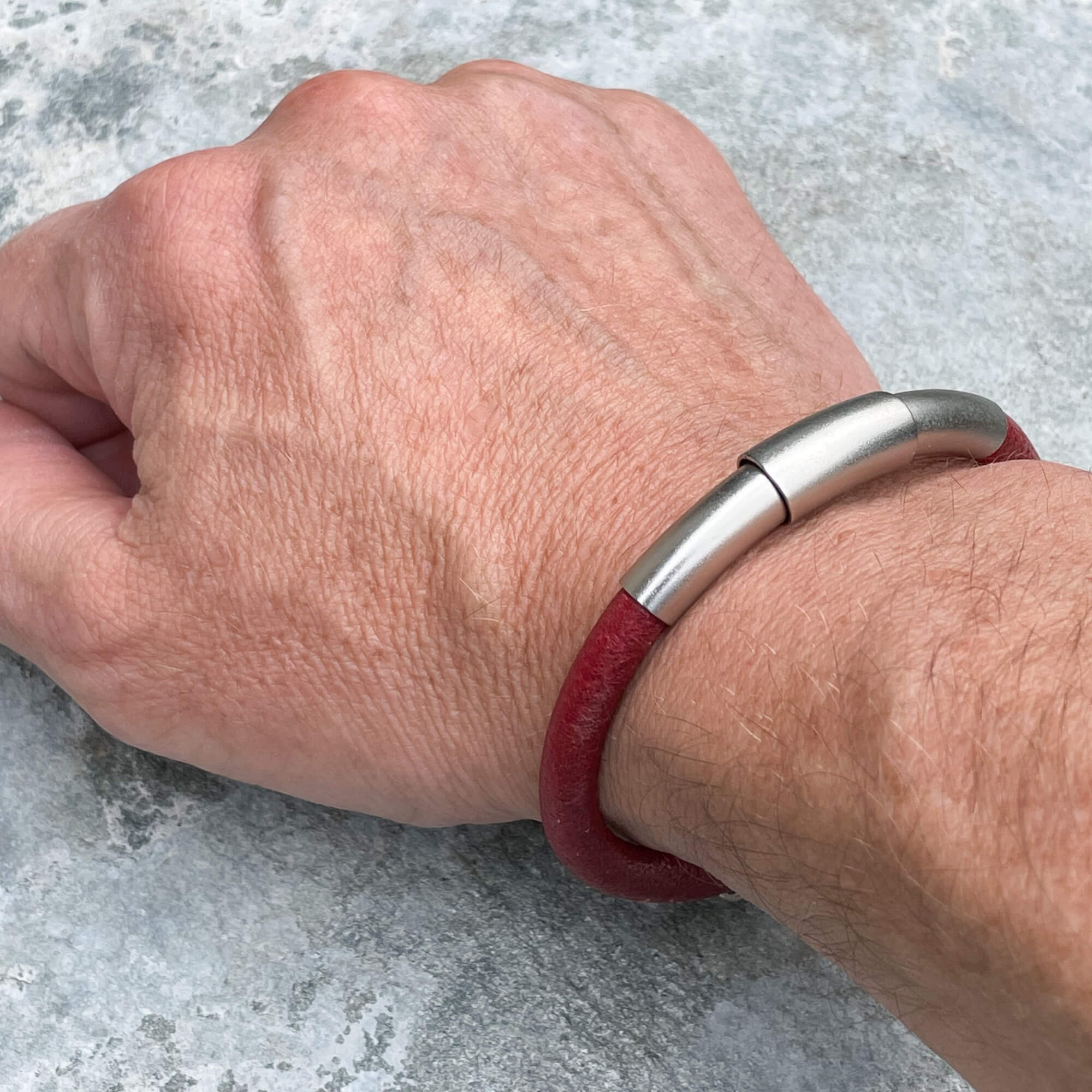 Red leather bracelet with silver colored band from stainless steel